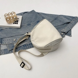 Detail of minimalist white canvas saddle bag with adjustable strap on denim jacket