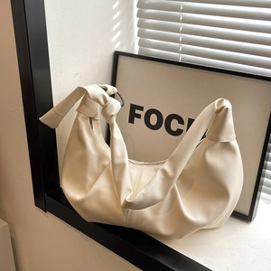 Minimalist off-white pebbled leather dumpling bag with knotted strap and slouchy design
