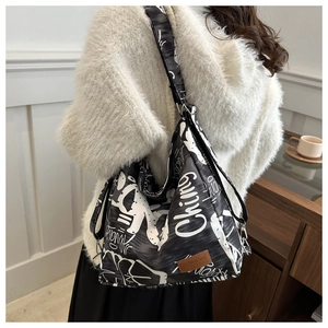 Detail of graffiti canvas shoulder bag with branded leather tag and side profile view