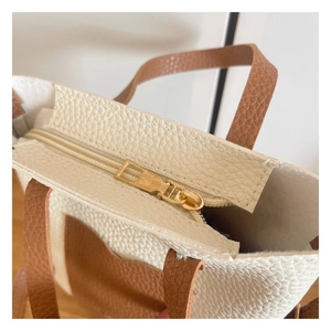 Close-up of golden metal zipper and textured white litchi grain leather stitching