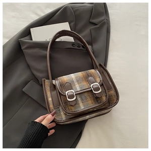 Dettaglio borsa vintage in lana scozzese con finiture in pelle e fibbie decorative