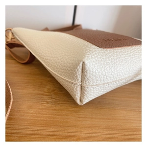 Close-up of contrast stitching and lychee grain leather on the crossbody bag base