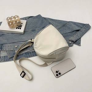 Detailed top view of off-white canvas crossbody bag with adjustable strap and lifestyle props