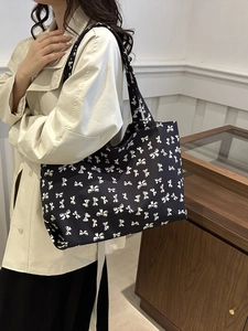 Close-up of black tote bag featuring white bow patterns on high-quality fabric material
