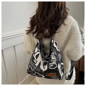Detail of black canvas tote bag with white graffiti letters and brown leather patch