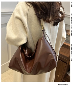 Detail of dark brown leather tote bag with adjustable strap and gold metal buckle