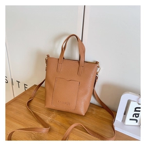 Close-up of brown litchi pattern leather tote bag with FASHION text and gold metal hardware
