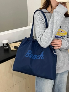 Detail of navy nylon tote bag with blue Beach embroidery and drawstring closure