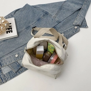 Top view of spacious cream canvas crossbody bag showing inner storage for daily items