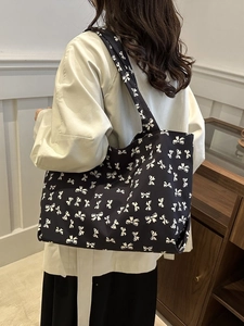 Close-up of lightweight tote bag with black and white bow prints on model's shoulder