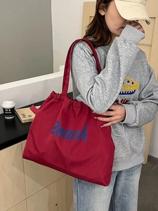 Close-up of red nylon tote bag with blue beach print and functional drawstring closure