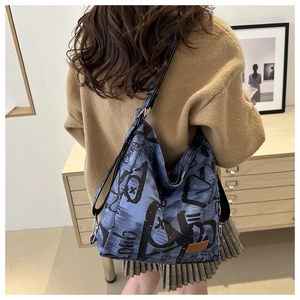 Detail of blue and black canvas tote bag with graffiti prints shown on a female model back