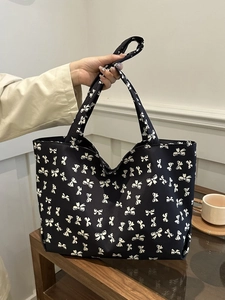 Close-up of a black nylon tote bag featuring white bow patterns and large capacity