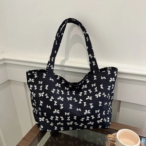 Detail of canvas tote bag featuring white bow patterns and wide shoulder straps
