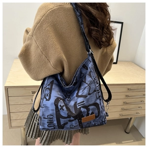 Detail of light blue graffiti canvas tote bag with adjustable strap and leather logo patch