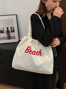 Detail of white nylon tote bag with red Beach letter print and drawstring closure
