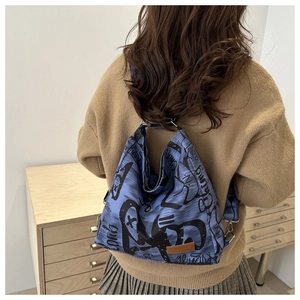 Close-up of blue graffiti canvas backpack with adjustable straps and fashion leather patch