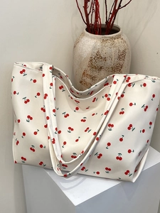 Détail d'un sac cabas en toile blanche avec motifs cerises rouges et bandoulières