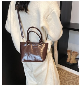 Detailed view of dark brown glossy bucket bag with unique knot handle design