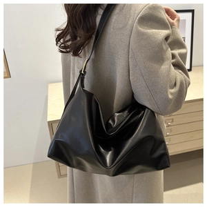 Fashionable black leather tote bag worn by a model, showing large capacity and soft texture