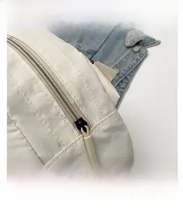 Detailed macro view of the smooth black metal zipper with a beige cord on the canvas bag