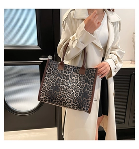 Detailed view of the leopard print tote bag with brown leather handles on a model