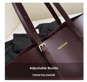 Detailed close-up of golden adjustable metal buckle on dark burgundy leather tote bag