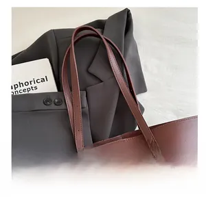 Detail of dark burgundy leather tote bag with slender straps over a grey blazer