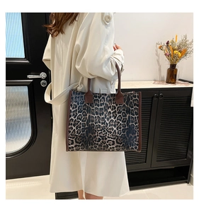 Detail of a large leopard print tote bag with brown handles worn with a beige trench coat