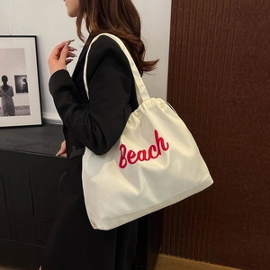 Off-white large nylon tote bag with red Beach letter print carried by a model
