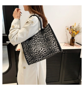 Detail of grey leopard print tote bag with black leather handles on a model