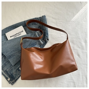 Close-up of brown leather tote bag with golden metal buckle and adjustable shoulder strap