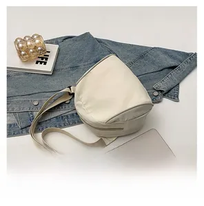 Detail of minimalist beige canvas crossbody bag placed on casual denim fabric