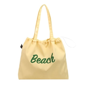 Minimalist creamy yellow nylon tote bag with green Beach print and drawstring closure
