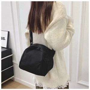 Detailed view of a black canvas crossbody bag being worn to show texture and capacity