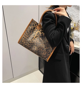 Detail of large leopard print tote bag styled on model with brown leather trim detailing