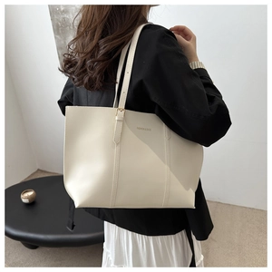 Close-up of cream leather tote bag with FASHION & BAGS text and gold hardware detail