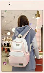 Detailed view of pink and white nylon backpack with mountain logo on adjustable straps