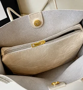 Detail view of the beige tote bag interior featuring magnetic closure and golden zipper pocket