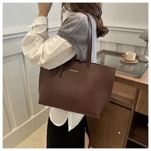 Close-up of brown litchi leather tote bag with FASHION & BAGS text and long straps