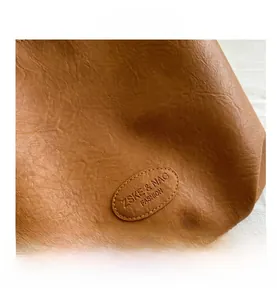 Close-up of brown leather tote bag detail with ZSKE & NAG FASHION brand embossed logo