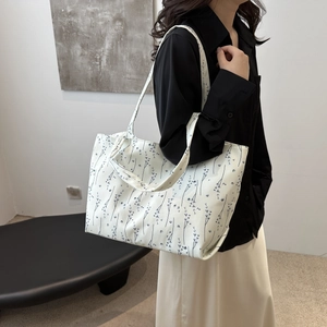 Modèle portant un grand sac cabas en toile crème avec un motif de plante bleue épuré