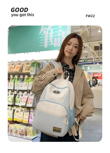 Detail of light blue and beige nylon backpack with mountain patch in a store setting