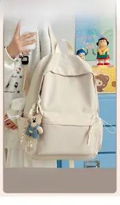 Detail of off-white canvas backpack with XINFEIDA embroidery and cute bear charm
