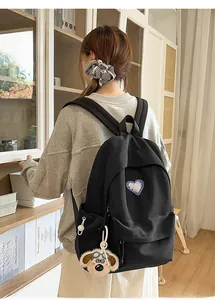 Detail of black backpack with purple heart embroidery and cute puppy plush pendant