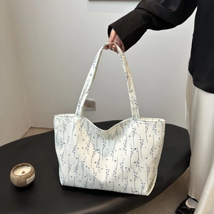 Détail du sac cabas en toile crème avec motifs floraux bleus et doubles poignées de transport
