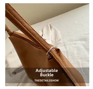 Close-up of adjustable strap buckle and stitching on brown vintage leather tote bag