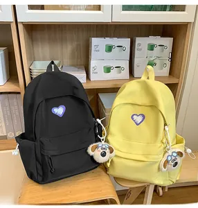 Detail view of nylon backpack featuring a purple heart embroidery and a plush dog keychain