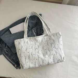 Détail d'un sac cabas en toile blanche avec imprimé floral minimaliste et anses résistantes