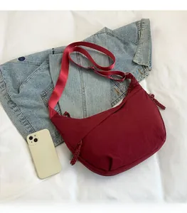 Détail du sac en croissant bordeaux avec comparaison de taille avec un smartphone